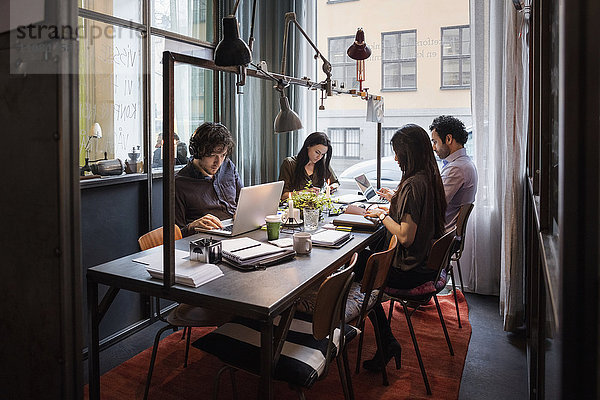 Bloggerinnen und Blogger arbeiten am Tisch im modernen Büro