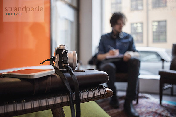 Nahaufnahme von Kamera und Smartphone auf Büchern mit Mann im Kreativbüro