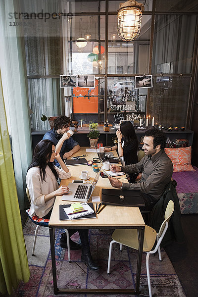 Großer Blickwinkel auf das kreative Geschäftsteam  das am Tisch im modernen Büro arbeitet.
