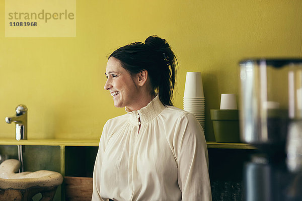 Fröhliche Kellnerin schaut weg im Coffee Shop