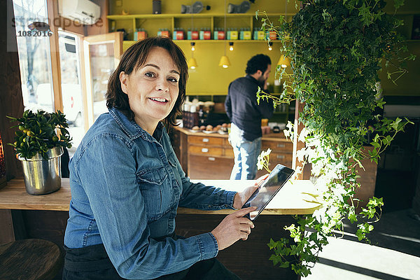 Porträt eines glücklichen Besitzers mit digitalem Tablett im Cafe