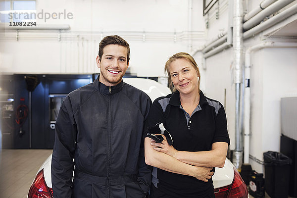 Porträt eines glücklichen Mechanikers mit Frau in der Werkstatt