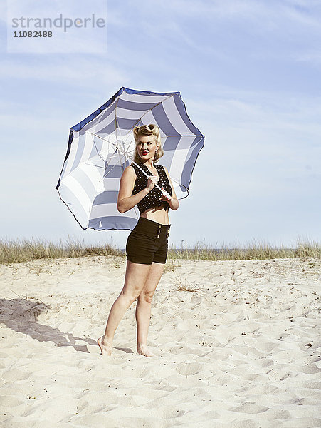 Junge Frau in Retrokleidung und mit Sonnenschirm