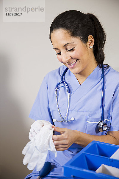 Krankenschwester zieht Handschuhe an