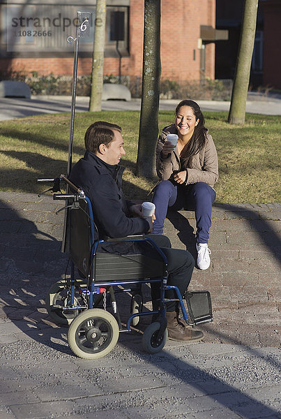 Junge Frau und Mann im Rollstuhl machen Kaffeepause