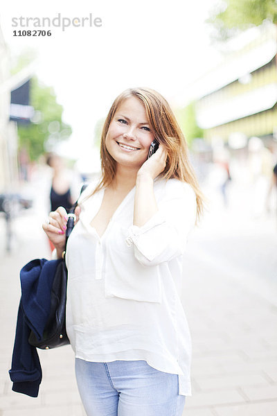 Lächelnde junge Frau  die mit einem Handy telefoniert  Vaxjo  Smaland  Schweden