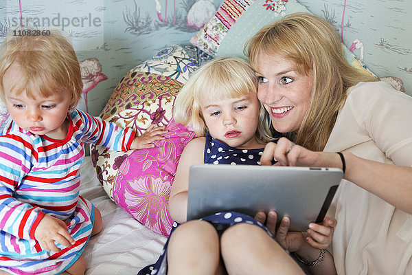 Mutter mit zwei Kindern und einem digitalen Tablet