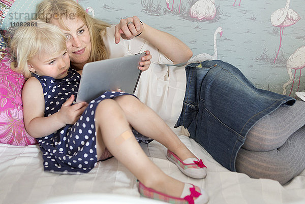 Mutter mit Kindern  die ein digitales Tablet benutzen