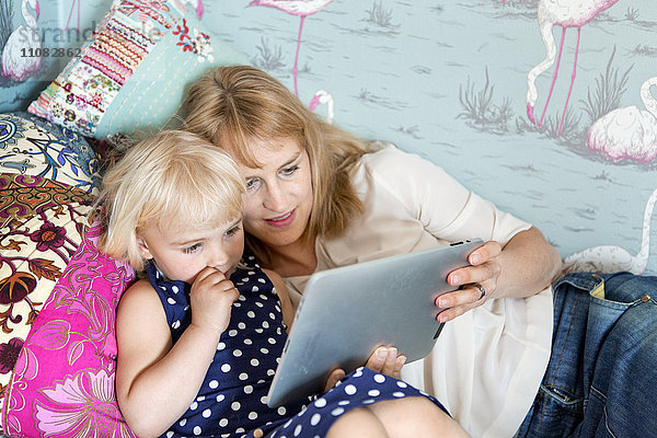 Mutter mit Tochter  die ein digitales Tablet benutzt