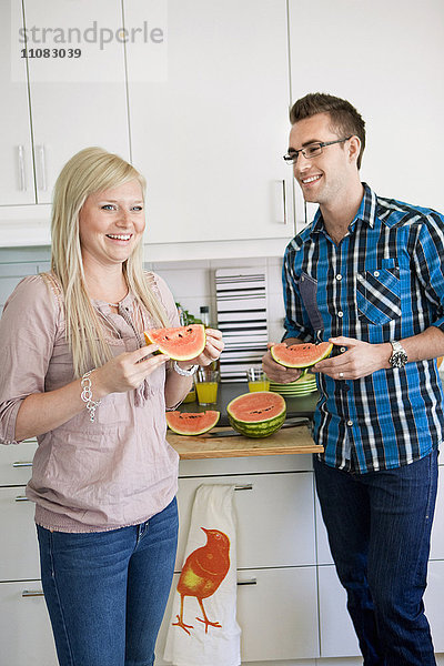 Junges glückliches Paar in der Küche isst Wassermelone