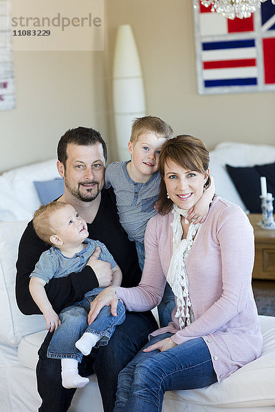 Familie mit zwei Kindern auf dem Sofa sitzend