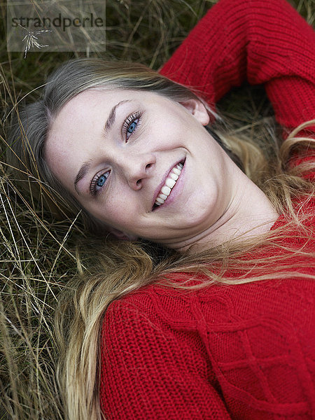 Porträt einer jungen Frau  die sich im Gras ausruht