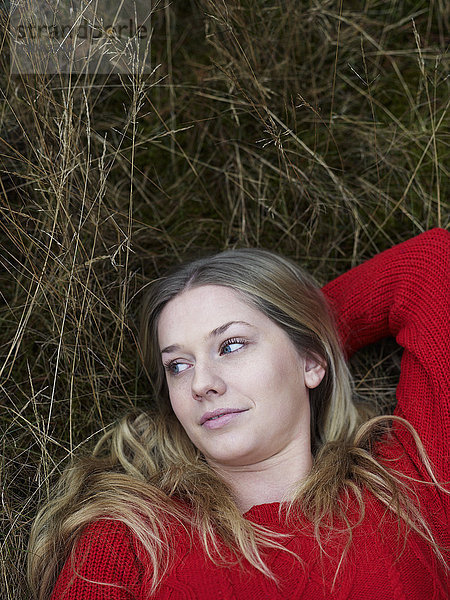 Porträt einer jungen Frau  die sich im Gras ausruht
