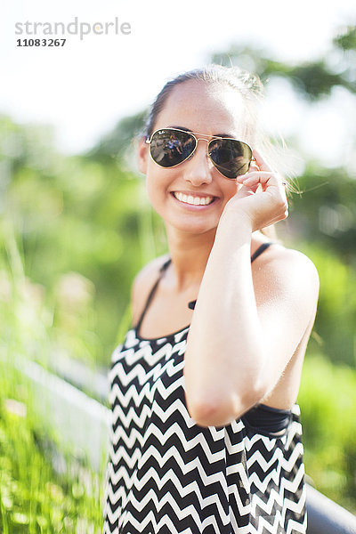 Porträt einer lächelnden jungen Frau mit Sonnenbrille