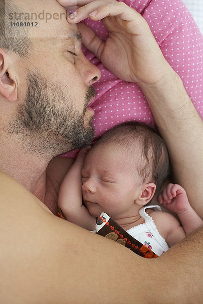 Vater schläft mit neugeborenem Mädchen