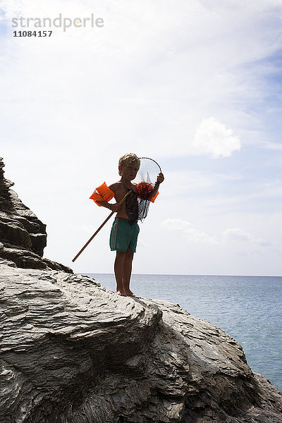 Junge an der Küste mit Fischernetz  Griechenland