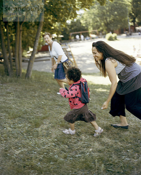 Mädchen mit Mutter läuft auf Rasen