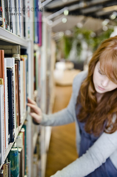 Junge Frau wählt ein Buch in der Bibliothek aus