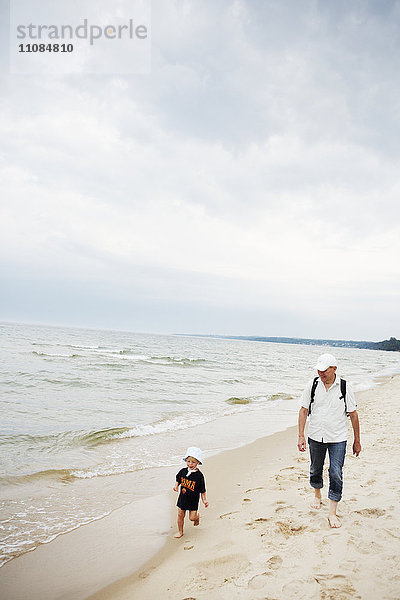 Großvater und Enkel gehen am Strand spazieren  Schweden.