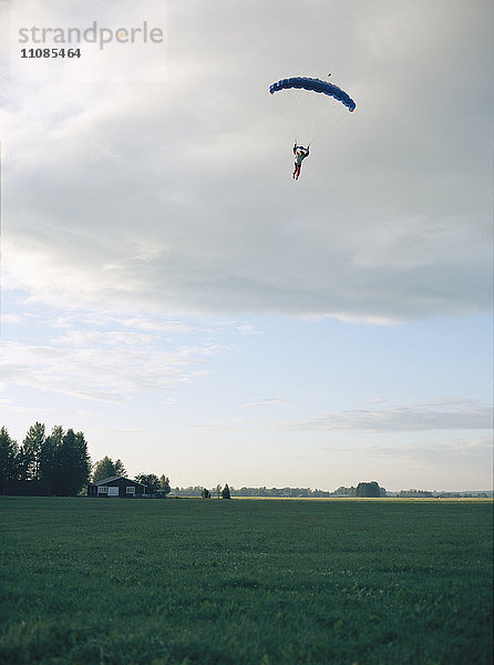 Fallschirmspringer im Himmel über einem Feld