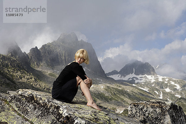 Blonde Frau im schwarzen Kleid in einer Berglandschaft  Schweiz.