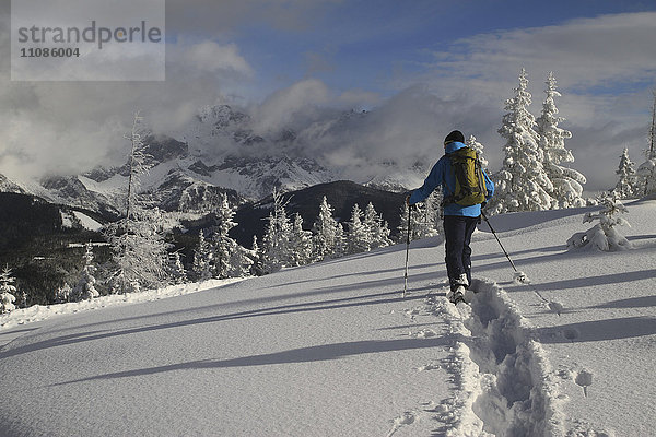 Mann in warmer Kleidung geht auf schneebedecktem Feld gegen die Berge