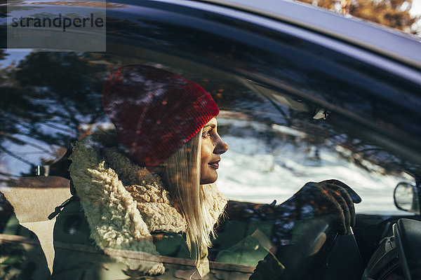 Frau in warmer Kleidung fährt Auto