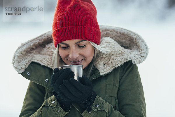 Nahaufnahme einer jungen Frau beim Kaffeetrinken im Winter