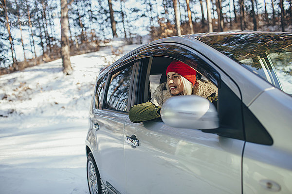 Glückliche junge Frau im Auto im Winter