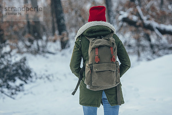 Rückansicht einer jungen Frau mit Rucksack auf schneebedecktem Feld
