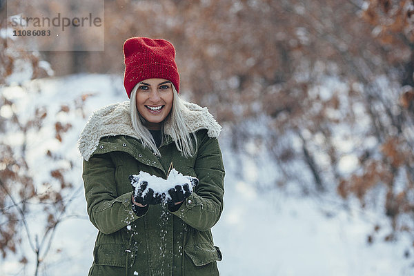 Porträt einer lächelnden jungen Frau mit Schnee auf dem Feld