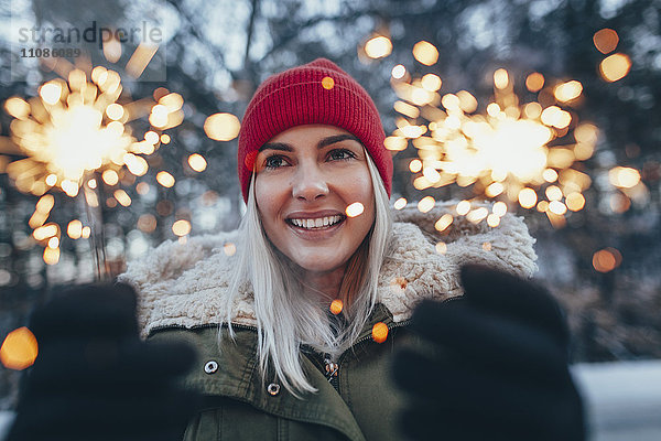 Glückliche Frau  die im Winter Wunderkerzen hält.