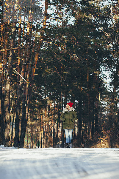 Volle Länge der Frau beim Wandern im verschneiten Wald