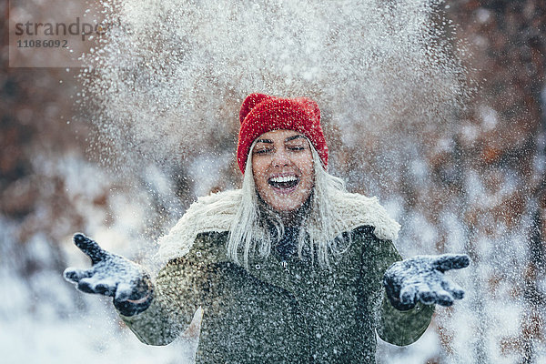 Glückliche junge Frau beim Spielen im Schnee