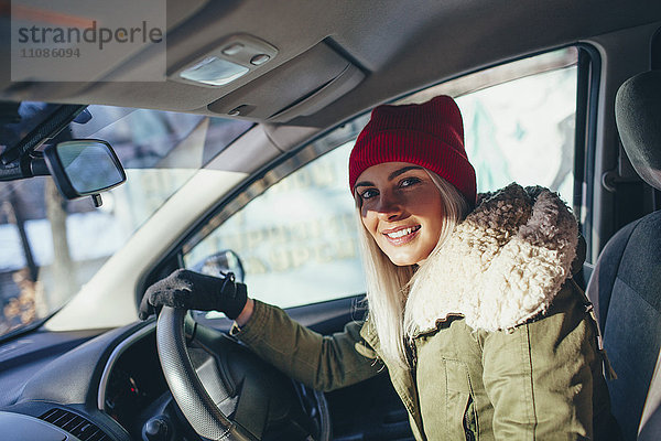 Porträt einer fröhlichen Frau in warmer Kleidung beim Autofahren