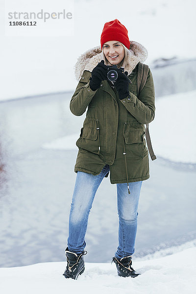 Schöne junge Frau  die im Winter durch die Kamera fotografiert.