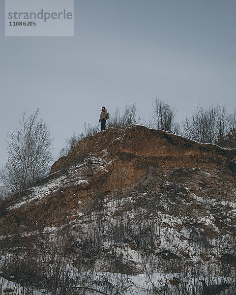 Flachwinkelansicht des Wanderers  der im Winter auf dem Berggipfel steht.