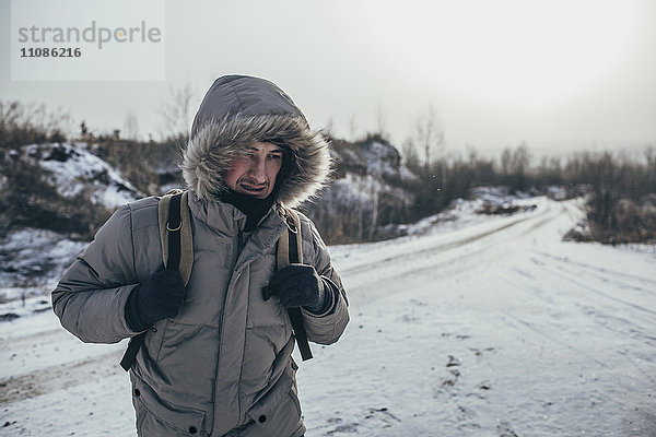 Wanderer mit Rucksack im Stehen auf verschneiter Landschaft