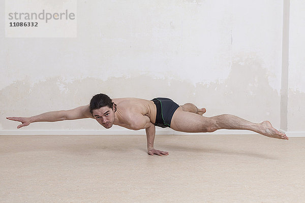 Porträt eines selbstbewussten Mannes  der Arm-Balance-Yoga-Übungen macht.