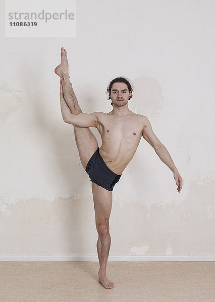 Porträt eines selbstbewussten Mannes beim Yoga vor weißem Hintergrund