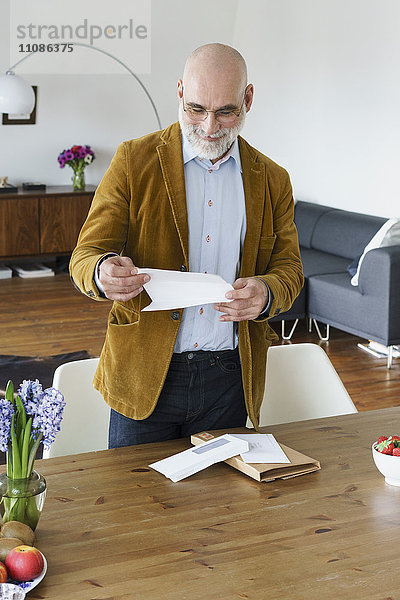 Erwachsener Mann liest Brief an Tisch zu Hause