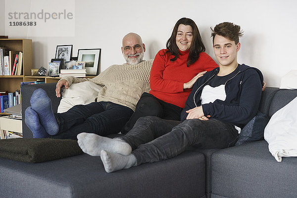 Porträt einer glücklichen Familie  die zu Hause auf dem Sofa sitzt.