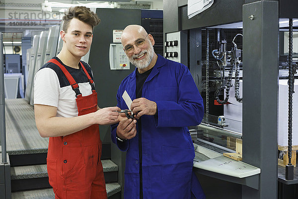 Porträt der Arbeiter  die das Werkzeug halten und an der Druckmaschine stehen