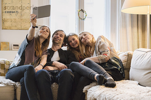 Glückliche vierköpfige Familie  die Selfie zu Hause durch ein digitales Tablett nimmt.