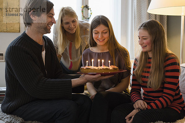 Glückliche Familie mit Geburtstagskuchen zu Hause