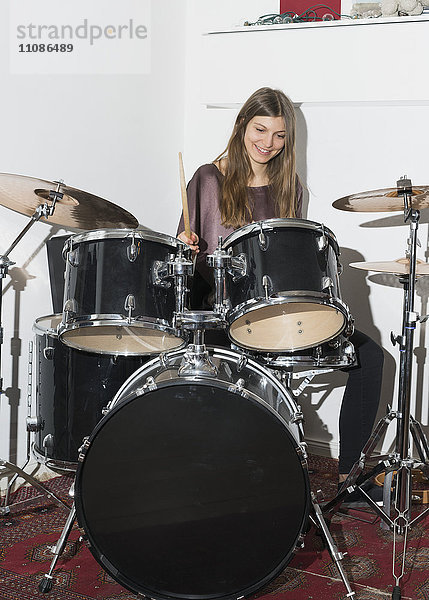 Fröhliche junge Frau beim Schlagzeug spielen
