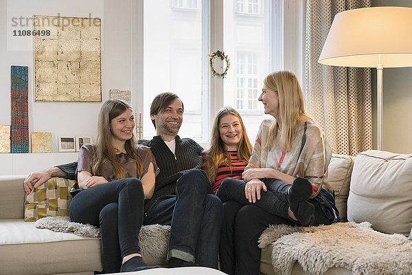 Eine glückliche vierköpfige Familie  die zu Hause auf dem Sofa sitzt.