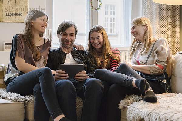 Glückliche Familie mit Vater mit digitalem Tablett im Wohnzimmer