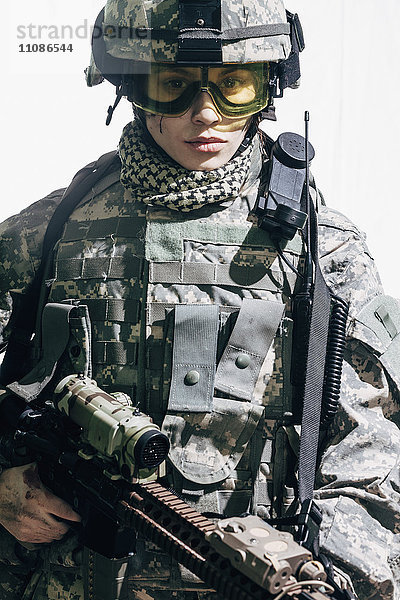 Porträt einer Soldatin mit Gewehr und weißem Hintergrund