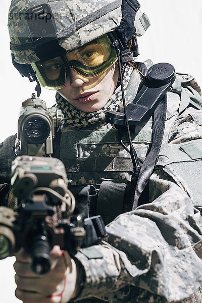 Armeesoldat mit Schutzbrille und Zielgewehr im Stehen auf weißem Hintergrund